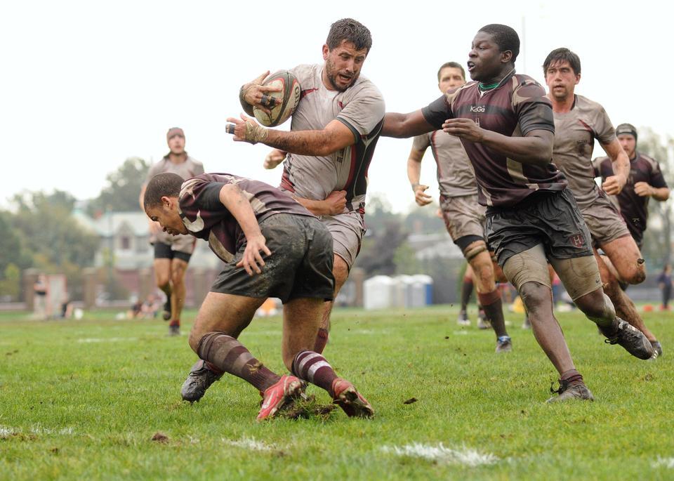 Obi Okwara ‘12 (right) helps take down a player from Brown in a rugby game on Saturday. The match ended in a loss for Harvard.