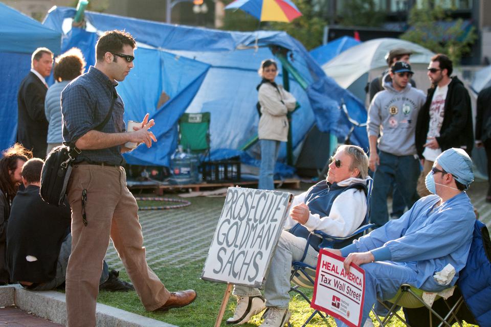 Michael, a retired teacher, and his son Justin, an unemployed surgical technician, discuss and debate the state of the economy and other topics with people at the Occupy Boston protest.
