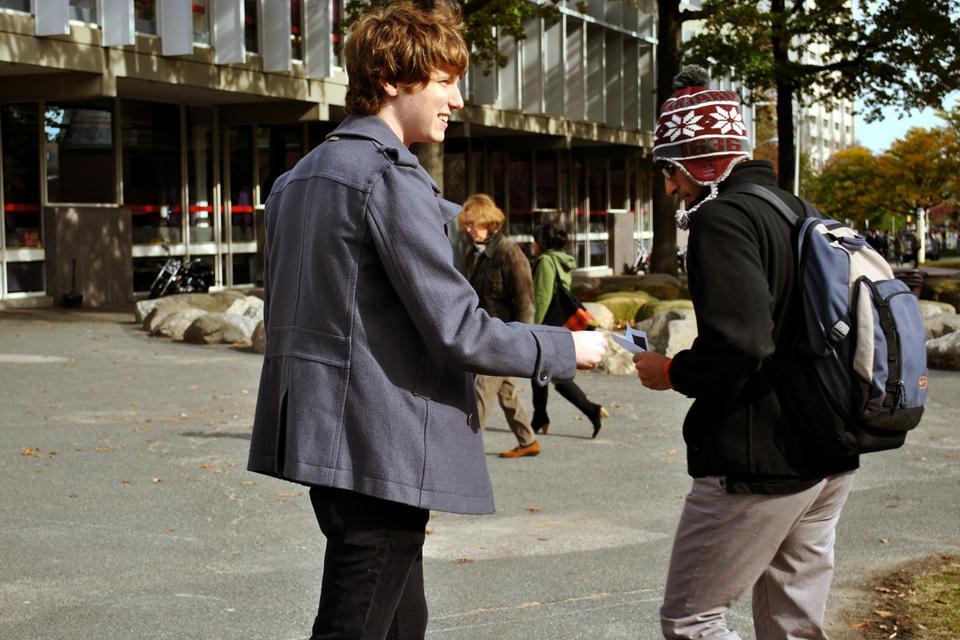 Neil Peterman, a physics research assistant, hands out fliers to students passing by the Science Center yesterday in a preliminary attempt to boost the number of participants in the "Occupy the Classroom Campaign."