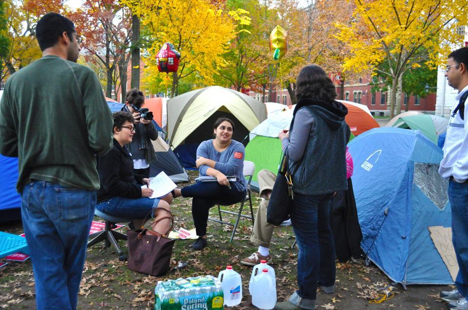 Amanda Haziz-Ginsberg, MTS ’12, is videotaped, photographed, and questioned as intrigued individuals gather around the Occupy Harvard movement.