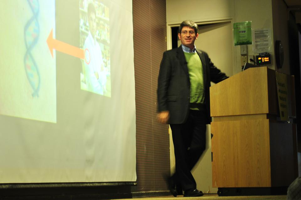 Author Carl Zimmer discusses his latest book about the scientific significance of tattoos at the Harvard Museum of Natural History on Tuesday night. Here, he's caught saying, "wow, that's geek love" when displaying a tattoo of a DNA helix with a loved-one's initials coded in amino acids.