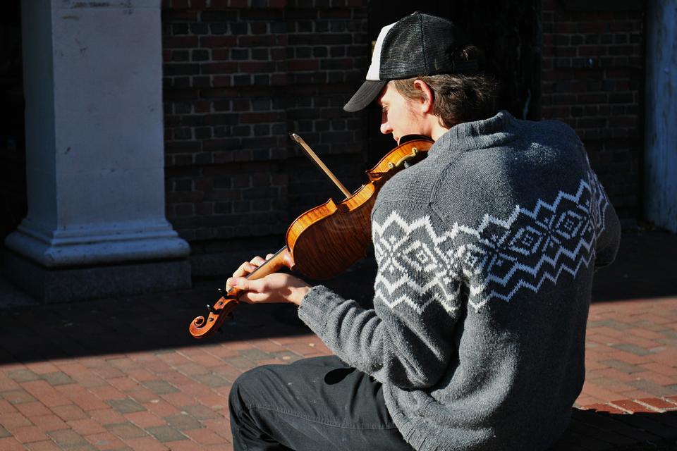 Alec G. Ellsworth, a student at the Extension school, spends his sunny day outside the Coop, playing fiddle as he's done for the past ten years. Although his earnings turn out to be about $4 an hour, he says "it's not for the money anyways."