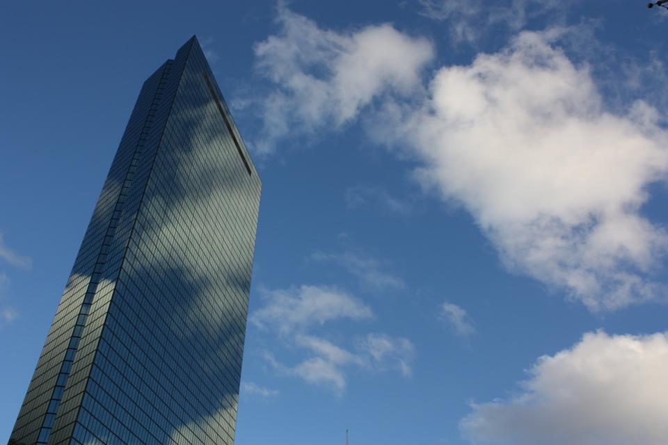 The John Hancock Tower reflects against a radiant blue sky. Upon its completion in 1976, the structure designed by Henry Cobb remains the tallest building in Boston and all of New England.