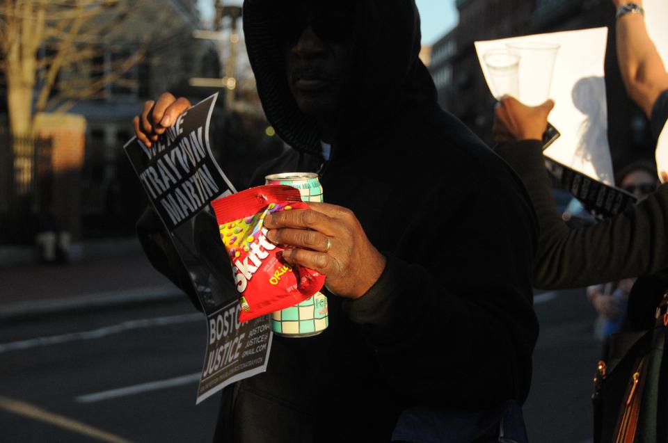 On Wednesday evening near the Harvard Square T Stop, a hooded citizen carries skittles and an iced tea, protesting the unwarranted murder of 17 year old Trayvon Martin, who was killed carrying those same items.
