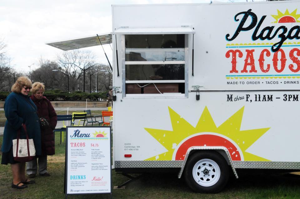 In the space that used to be the skating rink outside of the Science Center, customers look at the menu of Plaza Tacos, a new food truck run by Harvard University Dining Services.