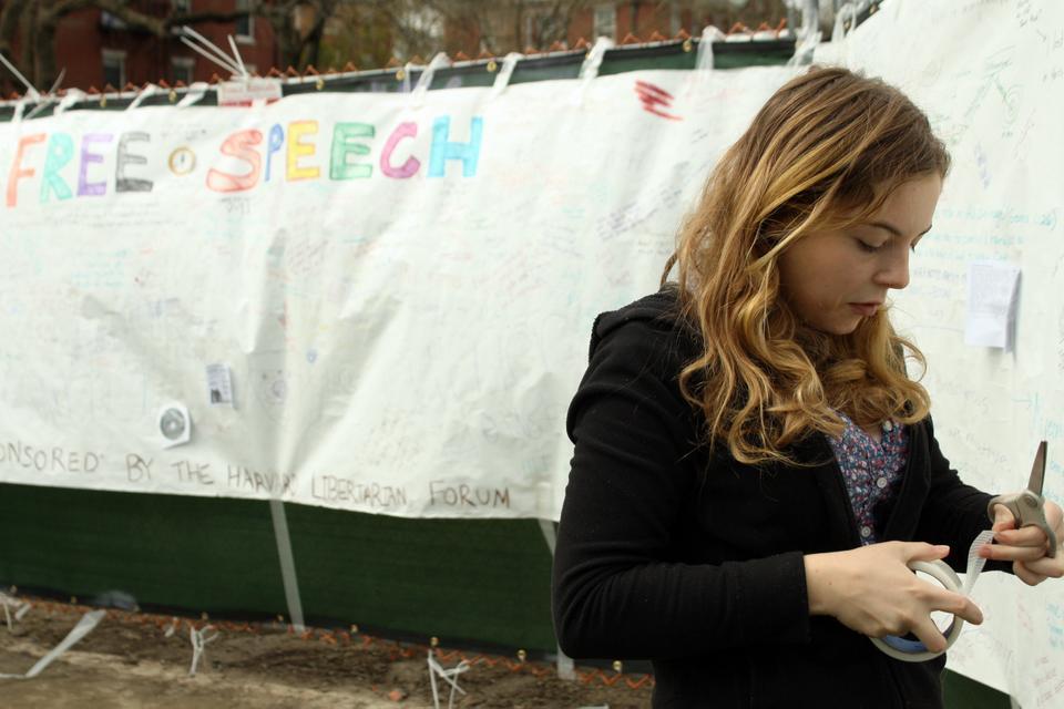 Corrine H. Curcie '15, a member of the Harvard Libertarian Forum, tapes up a portion of the "free speech banner" on the Science Center Plaza Thursday afternoon. The HLF, which sponsored the banner, hopes to draw attention to Harvard's free speech policies in light of the school's recent inclusion on the Foundation for Individual Rights in Education's annual "12 Worst Colleges for Free Speech" list.