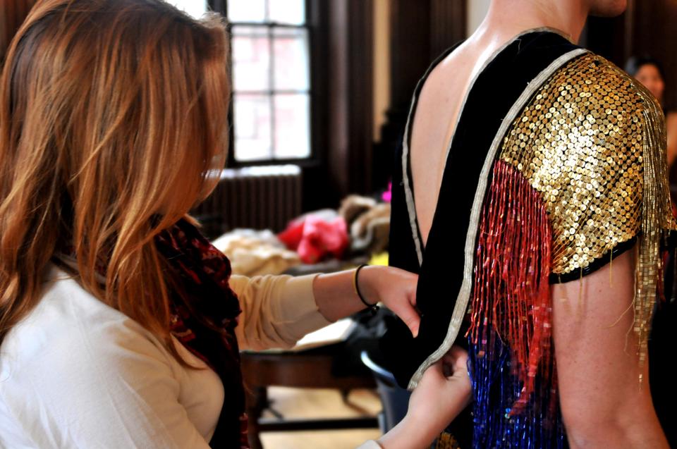 Rachel A. Gibian '15, costumer, makes final adjustments on the King Zinder costume of Alexander G. Smith '15. The assistant costumer is Angela J. Oh '15. 