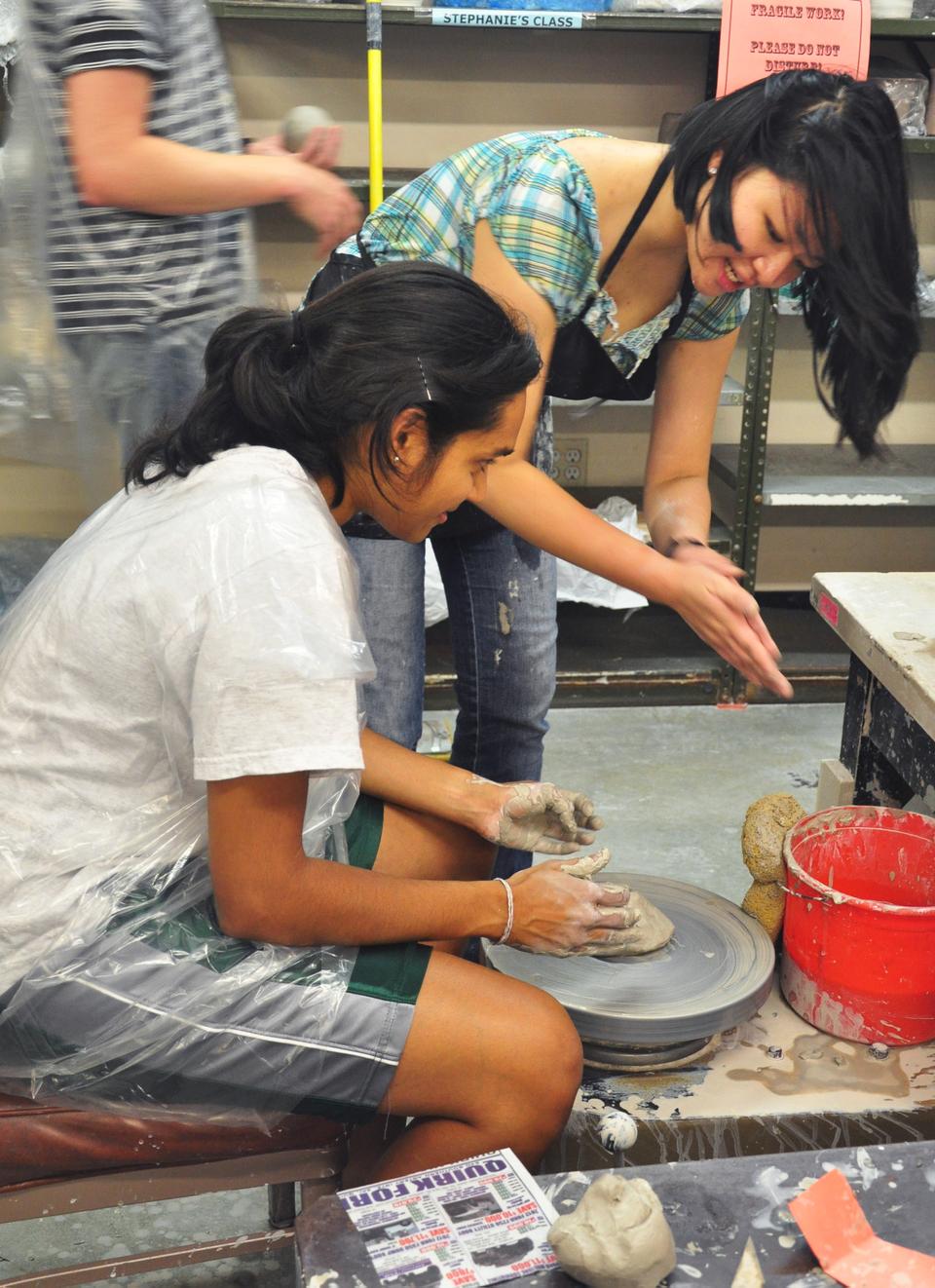 Cyatharine Alias '15 receives a brief tutorial on using the pottery wheel at Harvard's ceramics studio. Clay All Night, an event sponsored by the Office for the Arts on Friday, allowed students to model clay or spin on a wheel for free. Students also had the option of firing and glazing their works by paying or helping with clean-up after the event.
