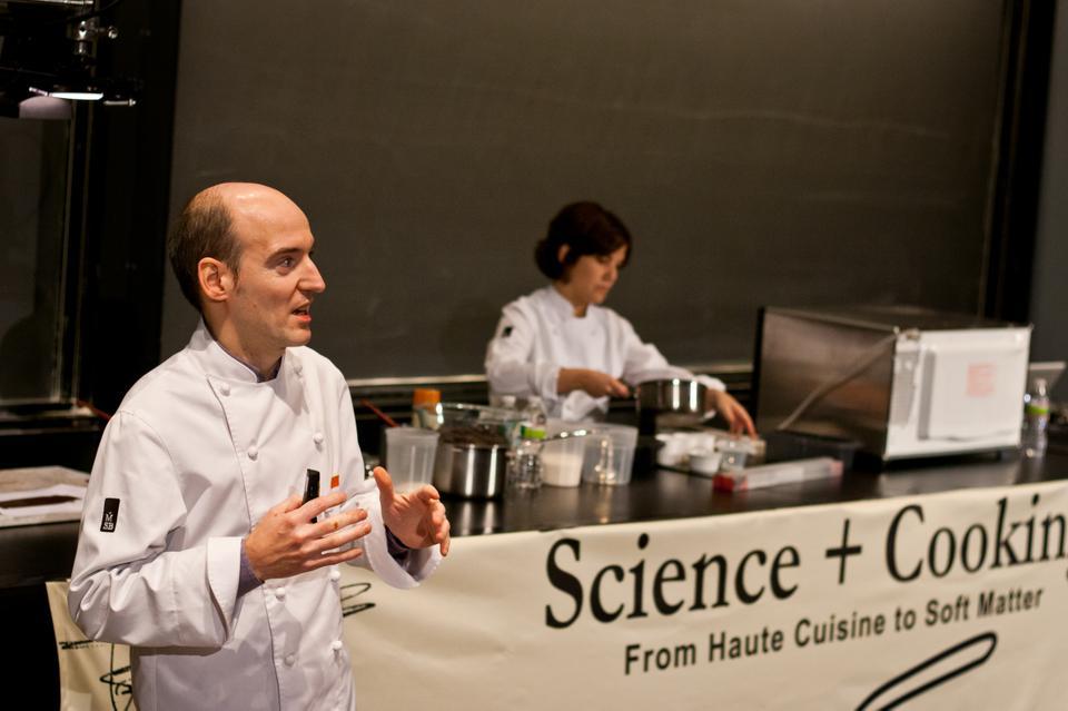 Master Chocolatier Enric Rovira lists chocolate recipes as Ingrid Farré prepares a sponge cake. Rovira explained the entire process of working with chocolate, including the collection, fermentation, and roasting of the raw plant.