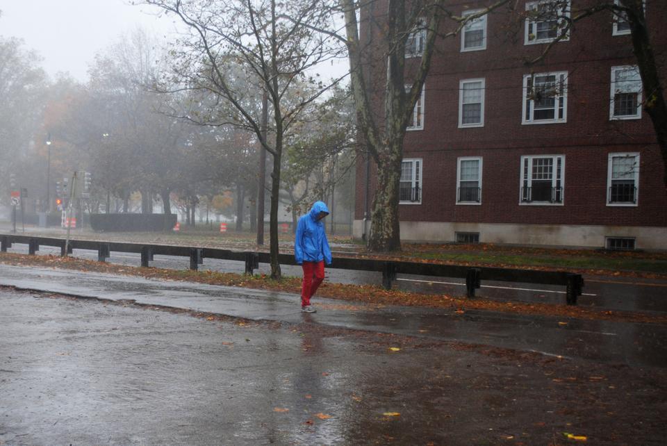 Cambridge residents try to stay dry Monday afternoon as both rain and wind become stronger. 