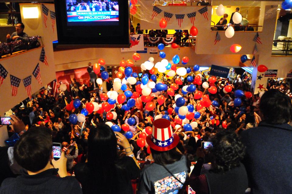 At 12:20AM after CNN released their projection that Obama had won the Presidential election, dozens of balloons drop onto spectators below at the Kennedy School's IOP election watch party.