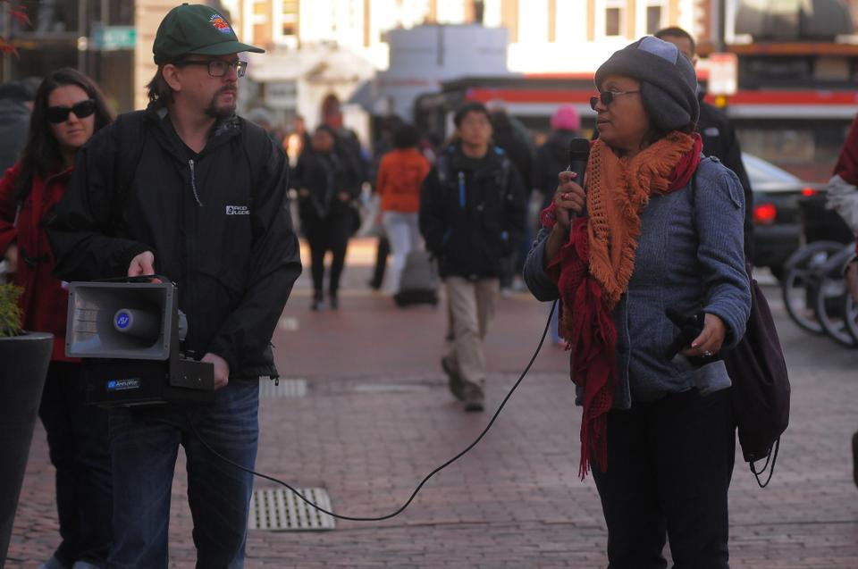 Johany Pilar, a clerk in the Harvard Yard Mail Center, joined by her HUCTW representative, Geoff Carens, addresses supporters gathered for a rally in front of the Holyoke Center. Pilar and Carens have been seeking more action on behalf of the University regarding Pilar's experience of sexual harassment in the mailroom. 