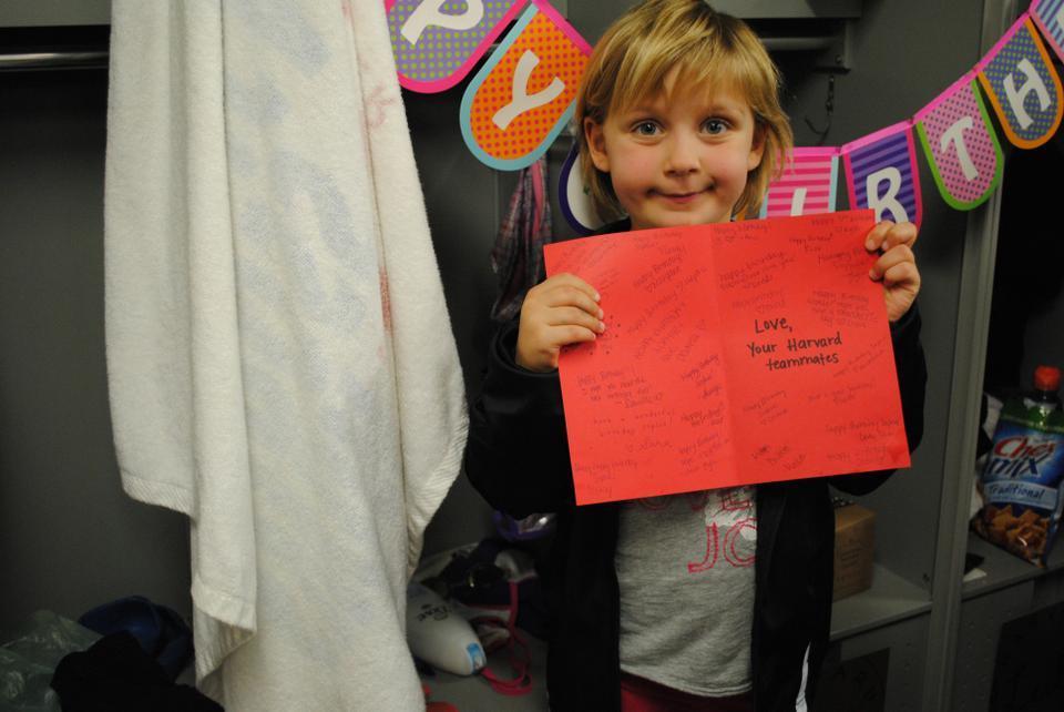 Five-year-old Sophie Pettengill, shown here in front of her varsity locker, joined the Harvard women’s swimming and diving team this year as part of Team IMPACT. Pettengill cheered on her teammates at last Friday’s meet. 