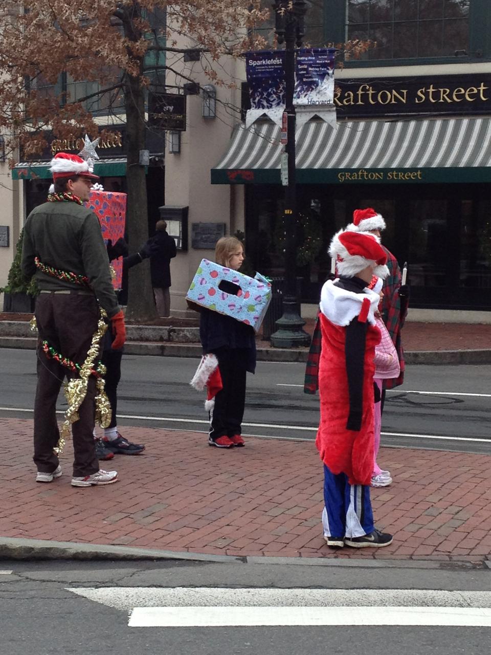 People in festive attire watch YuleFest, a Christmas-themed 5K with costumed runners in Cambridge that finished on Massachusetts Ave. 