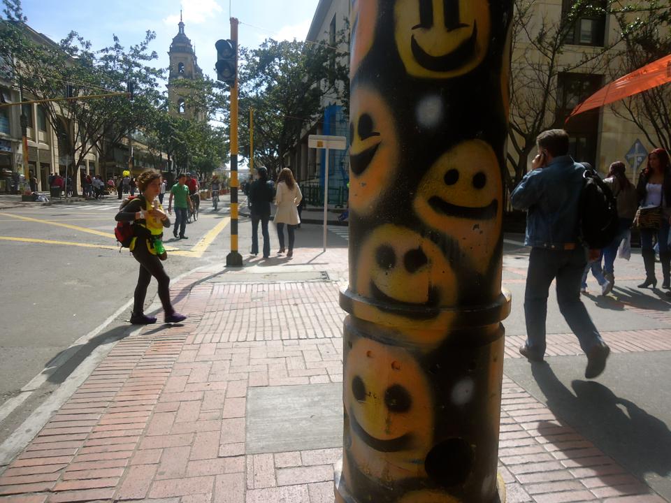 An overly optimistic street pole frames an intersection in Central Bogotá. 

