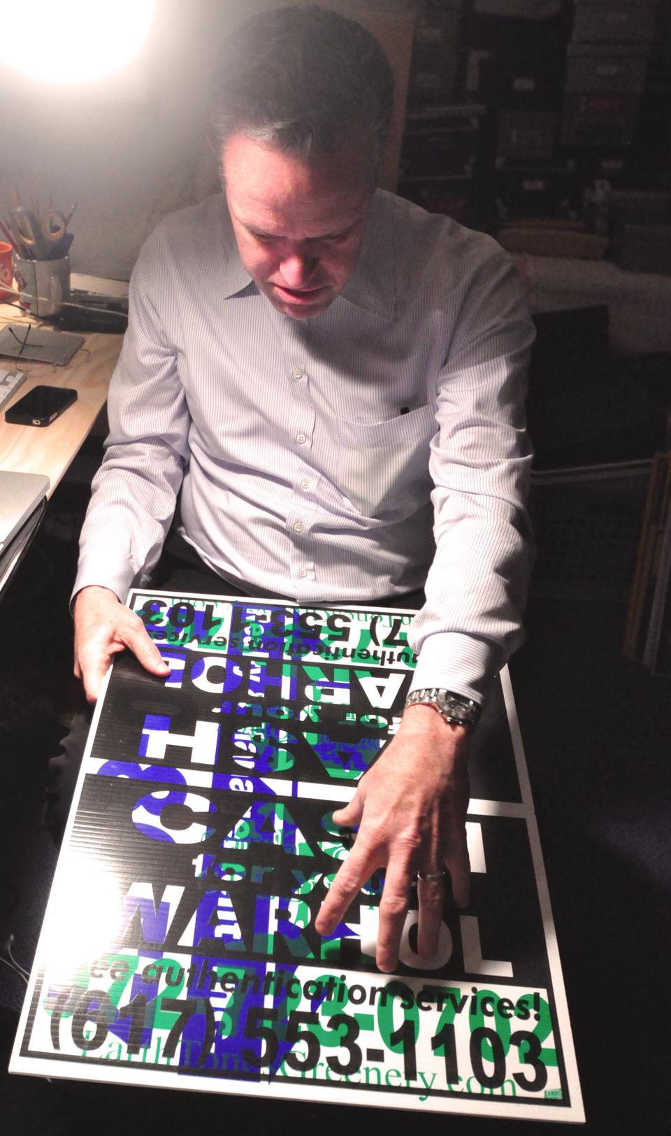 Geoff L. Hargadon ’76 holds a test print of one of the “Cash For Your Warhol” signs in his Somerville studio. 