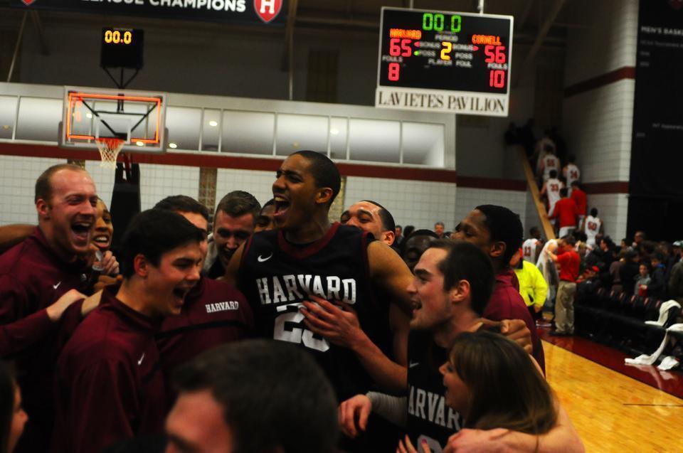 Sophomore Kenyatta Smith (center) and the Harvard men's basketball team celebrates after topping Cornell, 65-56, at Lavietes Pavilion on Saturday night. With the win, the Crimson clinched its third straight Ivy League title.