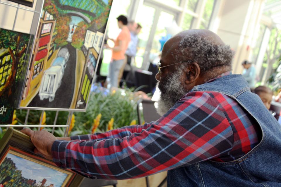 Boston artist Efon Elad adjusts his display at the City Heart Art Show, which features the work of homeless and low-income artists, in the Prudential Center on Saturday. Now in its third year, City Heart's one day show and sale included the work of seventy artists, including Elad, who creates art inspired by scenes from Cameroon and Boston at the St. Francis House shelter in Boston.