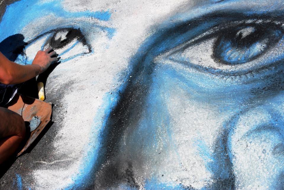 A woman kneels over her chalk drawing at the 30th Annual MayFair in Harvard Square. The Rotary Club of Cambridge’s annual Chalk on the Walk took place on Church St. throughout the day on Sunday.