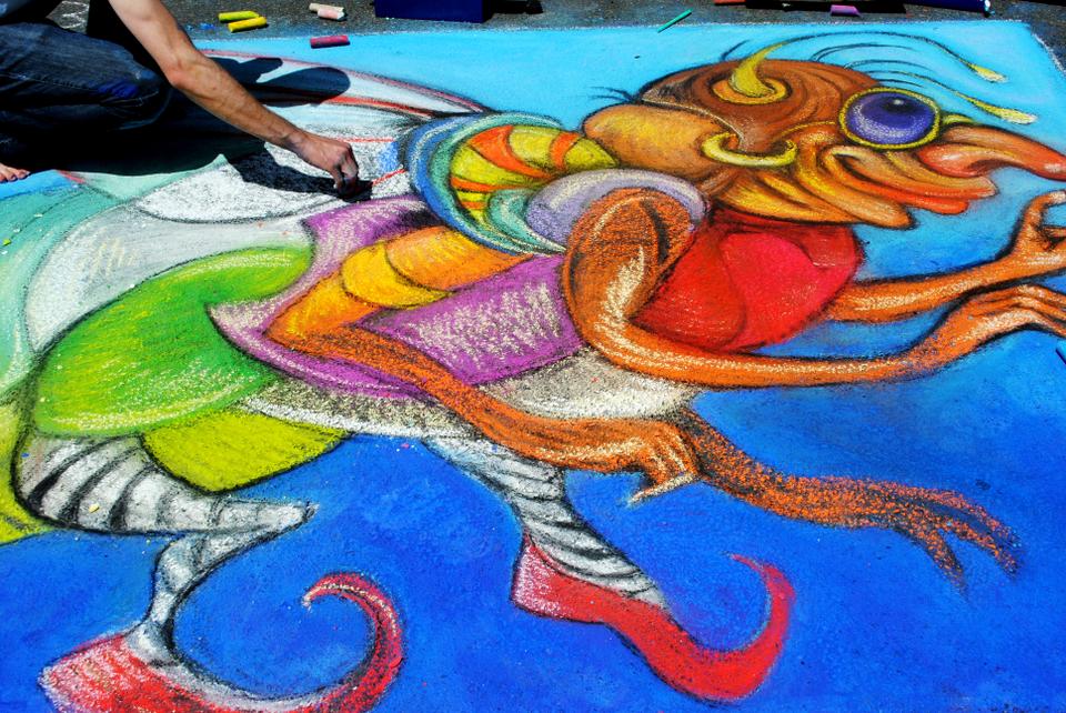 A man kneels over his chalk drawing at the 30th Annual MayFair in Harvard Square. The Rotary Club of Cambridge’s annual Chalk on the Walk took place on Church St. throughout the day on Sunday.