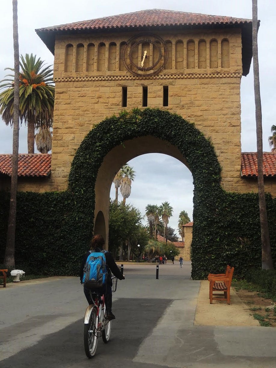A student bikes through the west entrance of the Main Quad at Stanford.