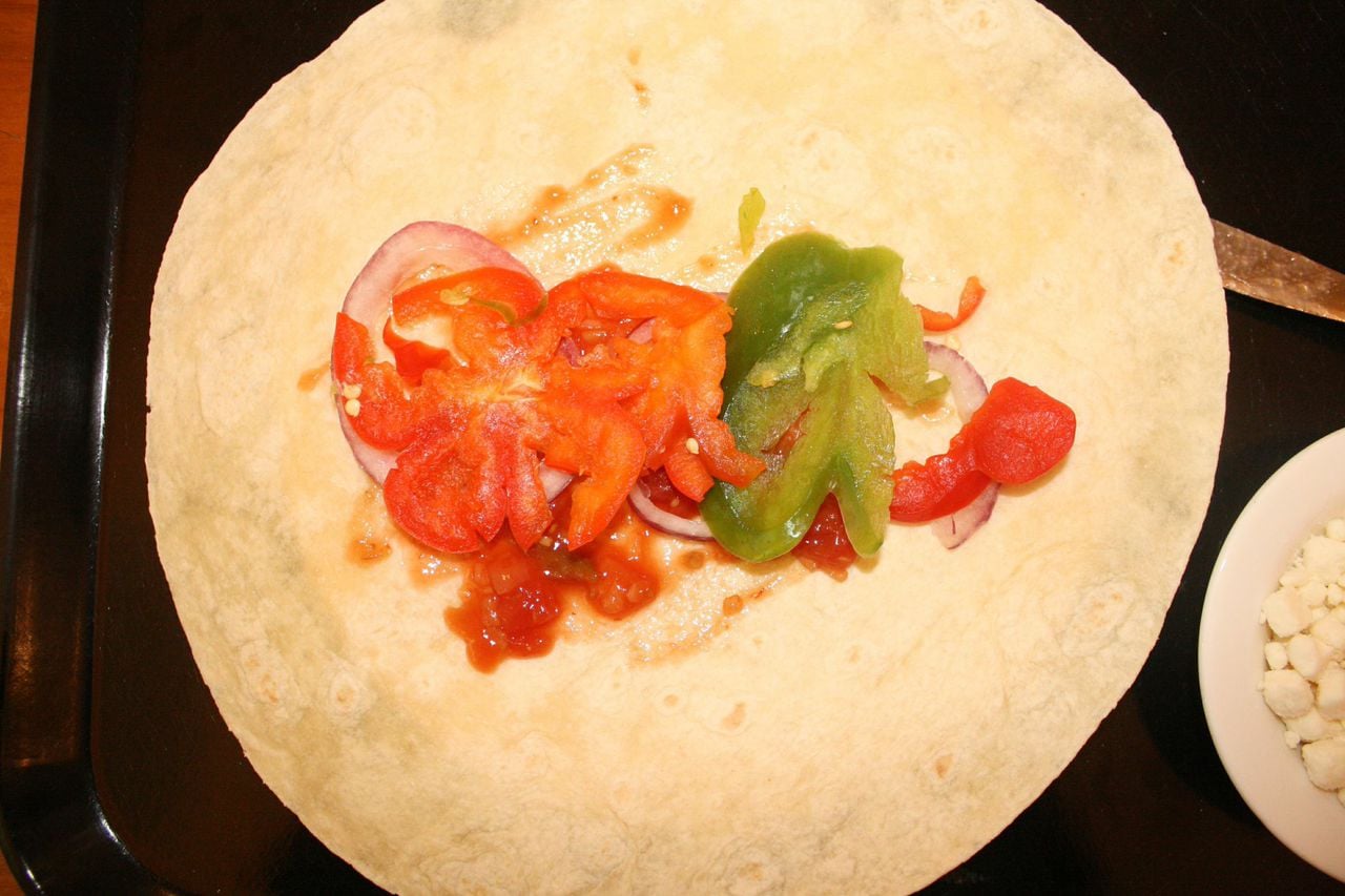 Add peppers and red onion to tortilla