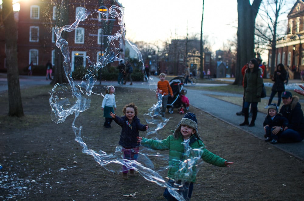 Children play with giant bubbles, courtesy of students in Harvard Yard.