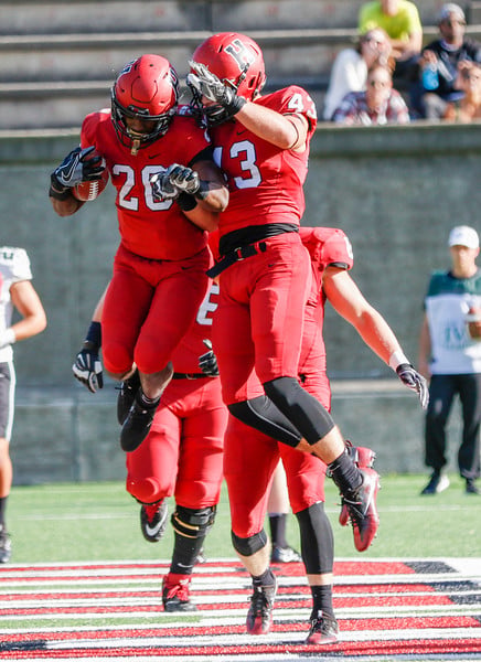Freshman Aaron Shampklin (20) celebrates with senior Ryan Antonellis (43) after giving the Crimson a two-score lead against Dartmouth. The backfield duo combined to haul in all three of freshman quarterback Jake Smith's touchdown passes against the Big Green.
