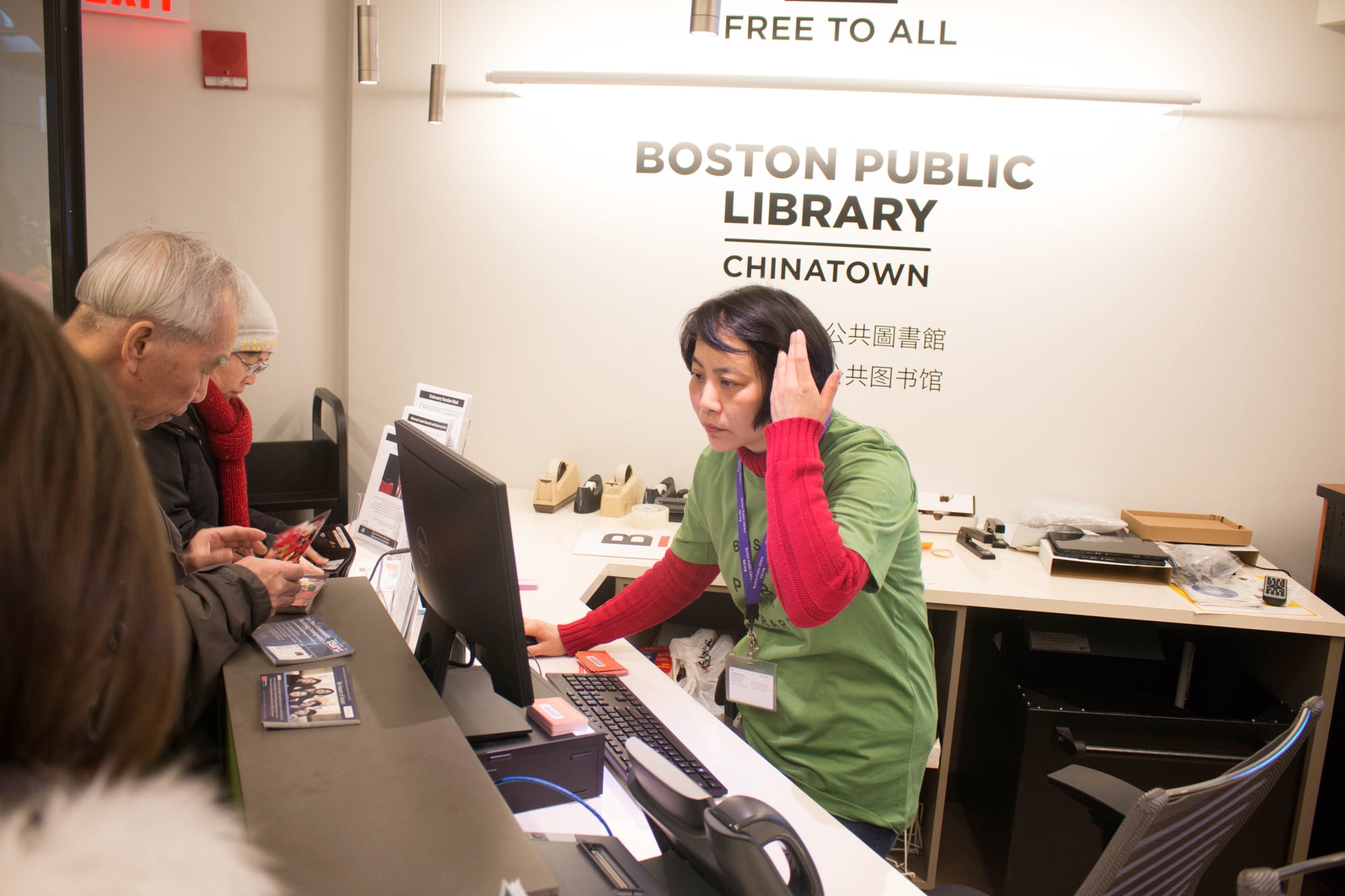 A librarian works at the circulation desk of the newly opened Boston Public Library Chinatown.