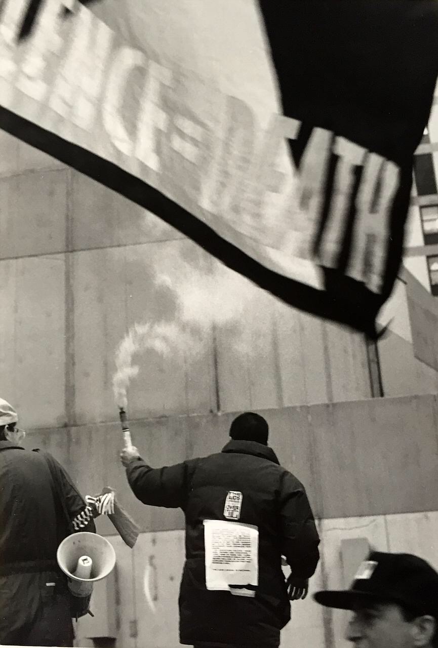 An ACT UP protester waves smoke at a protest outside Harvard Medical School.
