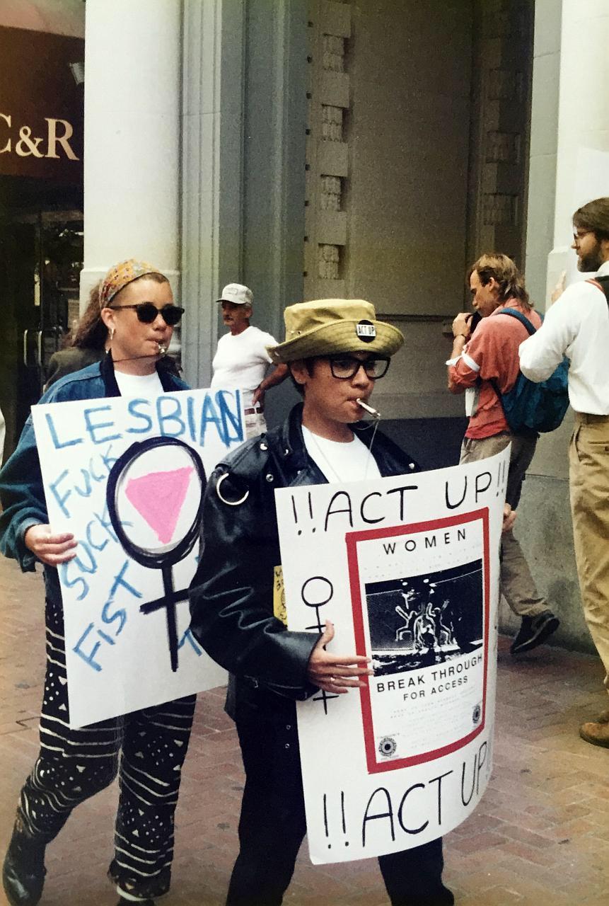At the International AIDS conference, two activists whistle while marching down the street, holding homemade posters.