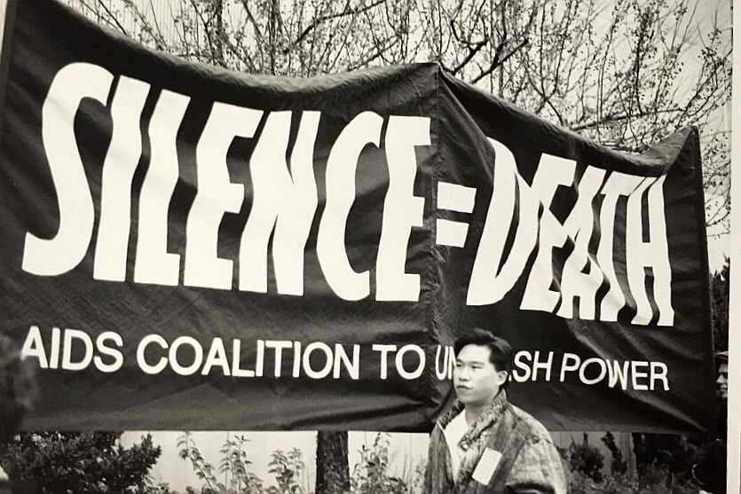 Leo L. Lai ’91 stands in front of a Silence = Death Poster poster at an ACT UP protest in Cambridge.
