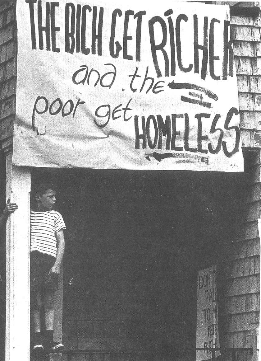 A sign on a building in Barry's Corner in Lower Allston in the 1960s. It reads, “The Rich Get Richer and the Poor Get Homeless.”