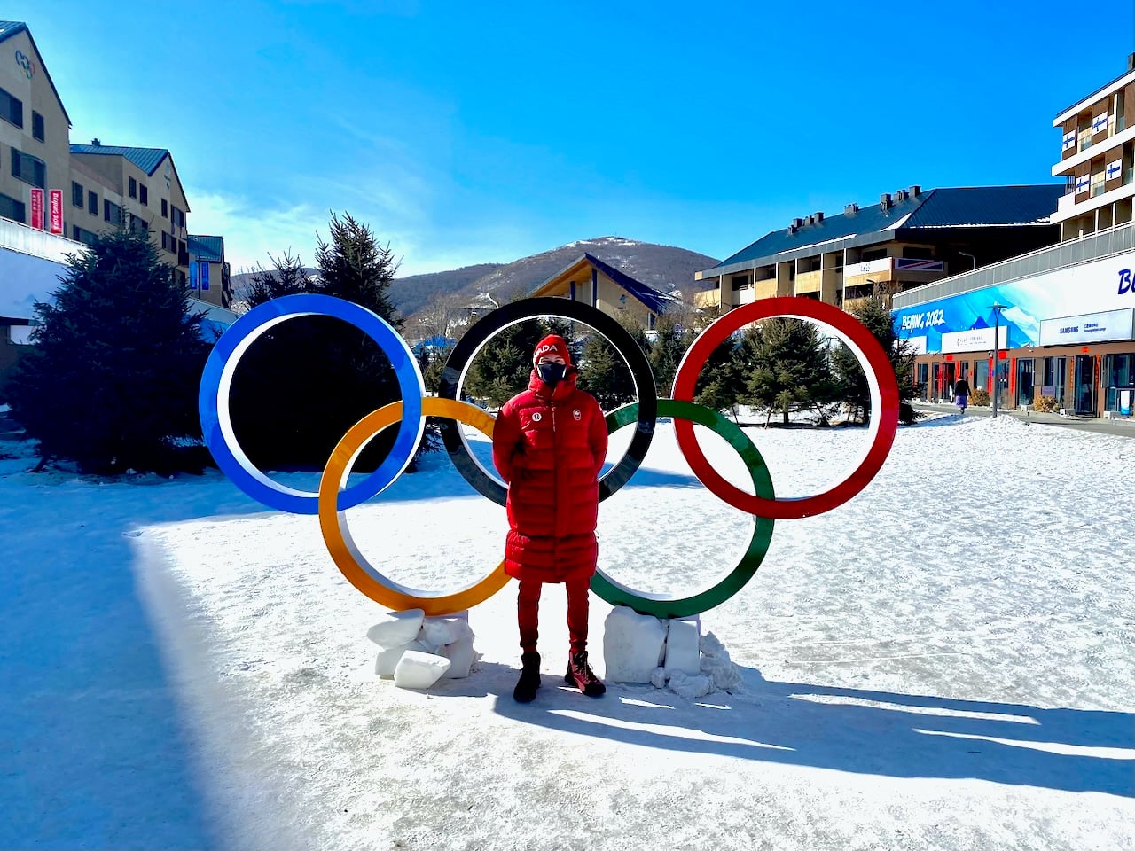 Rémi Drolet poses in front of the Olympic Rings during the 2022 Beijing Olympics.
