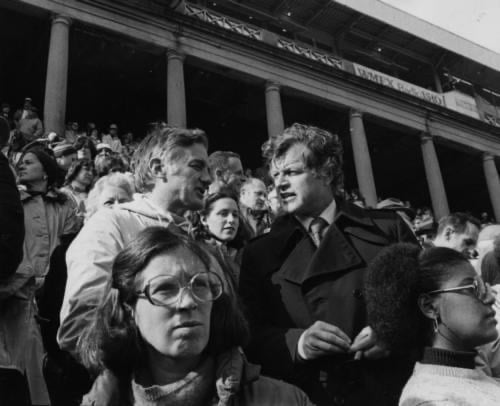 Bok speaks with former Senator Edward M. “Ted” Kennedy in a crowded stadium.