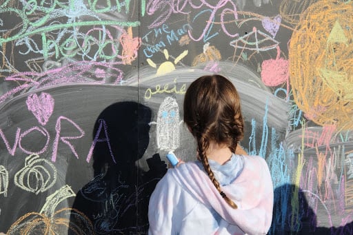 Young girl draws a ghost on the chalk wall at the Rugrat Rodeo.