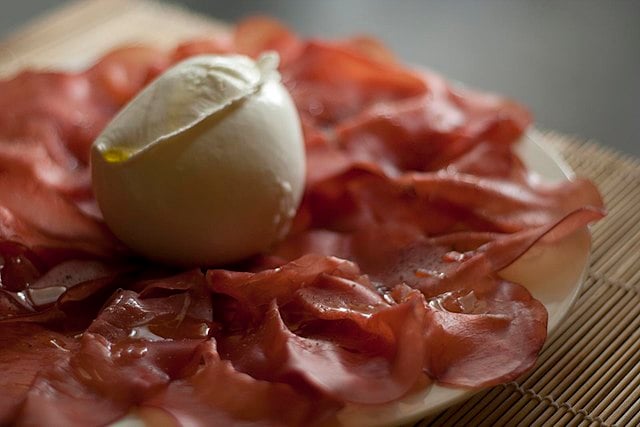 Bresaola served on a plate with a ball of mozzarella.