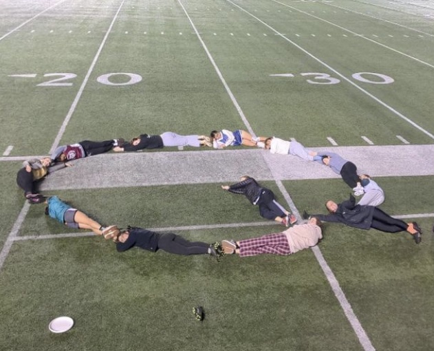 The frisbee team arranges themselves in a Q on the field. Harvard's women's frisbee team is called Quasar.