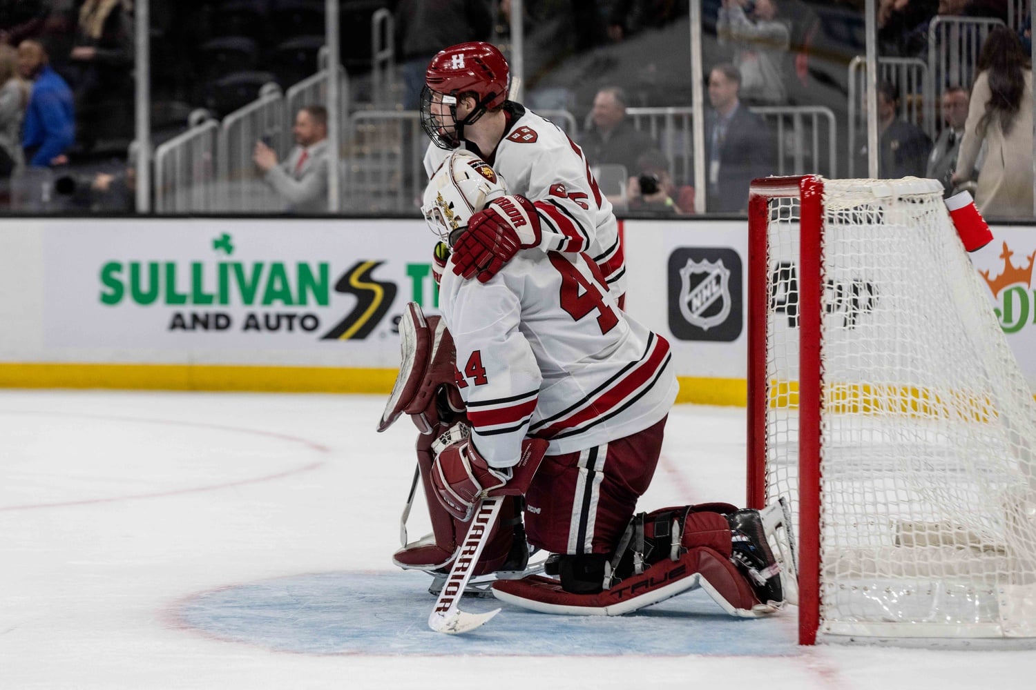 Senior goaltender Mitchell Gibson is consoled on the ice while Northeastern celebrates its Beanpot title on Monday night. Gibson was brilliant in the title game, making 27 saves.