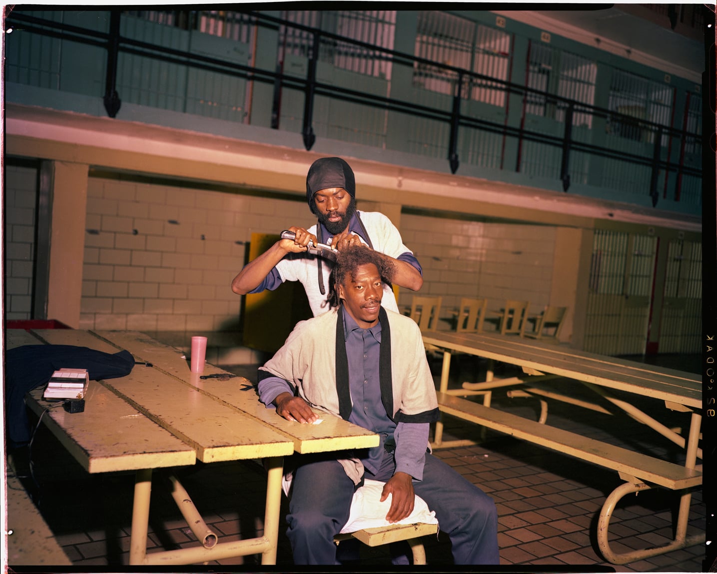 One man cuts another's hair inside Walpole State Prison in the 1980s.