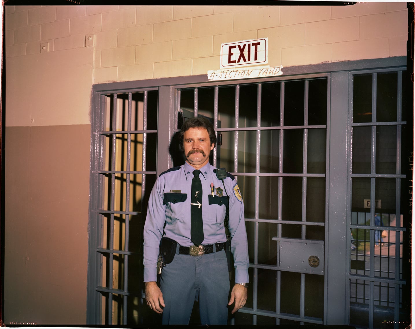 A corrections officer stands in front of a gate in Walpole in the early 80s.
