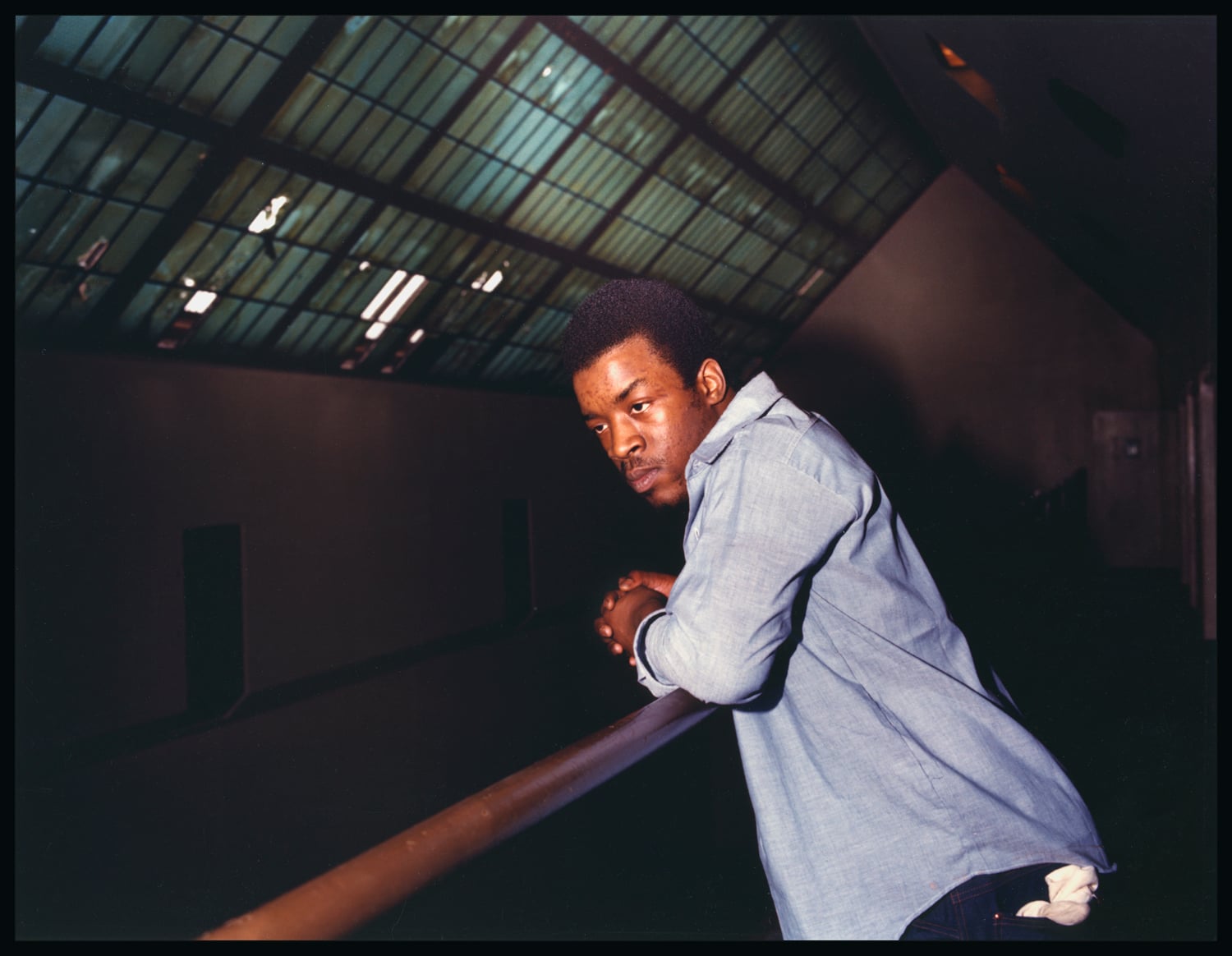 A man incarcerated at Walpole leans over a railing in his cell block.