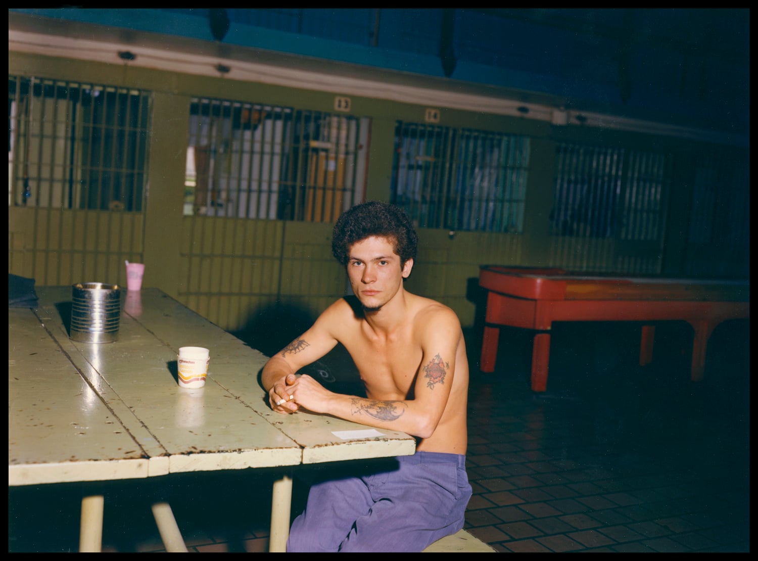A man incarcerated at Walpole in the 1980s sits alone at a communal table.