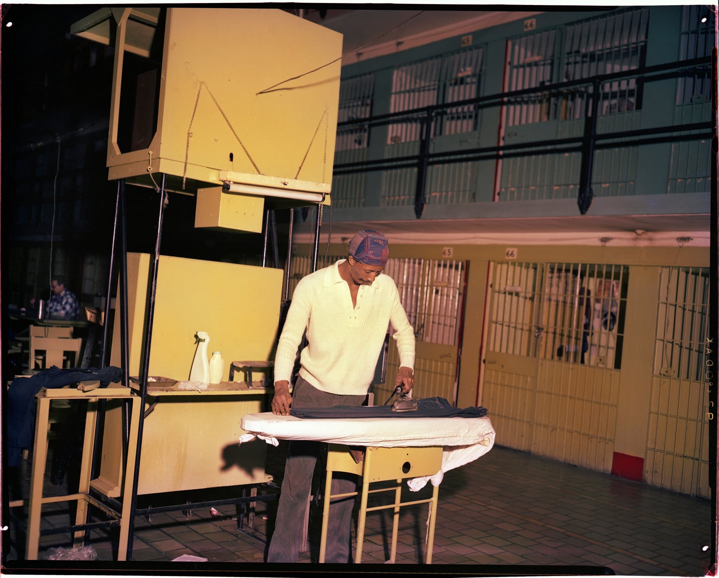 A man irons pants in a cell block at Walpole.