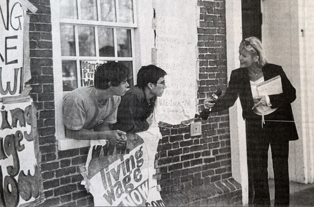 Two students leaning out of Massachusetts Hall window take interview with reporter during 2001 Progressive Student Labor Movement sit-in.