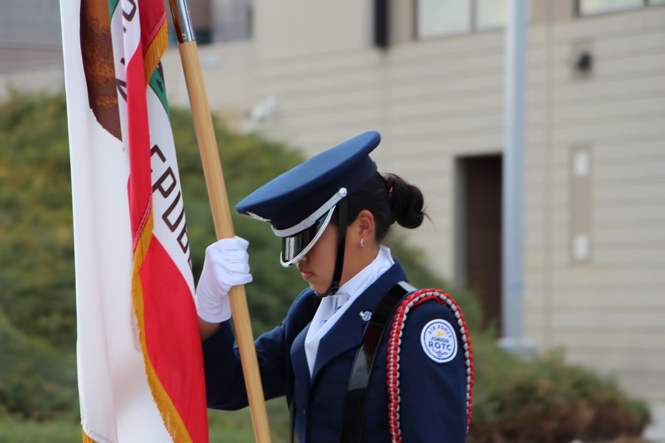 Anne Sun presents the colors at a high school football game as a member of the Air Force Junior Reserve Officer Training Corps.